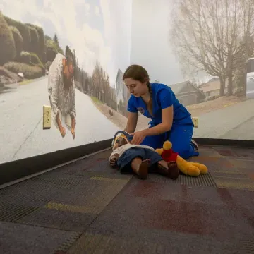 nursing student in AI simulation room with child mannequin on the floor 